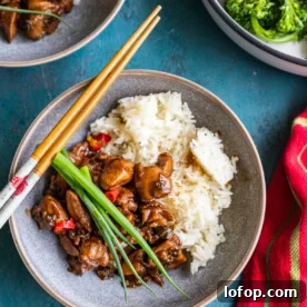 15-Minute Shanghai-Style Chicken Stir-Fry Recipe 11 A dish of Shanghai chicken with chopsticks laid over the top from above on a blue background and with a red stripy tea towel