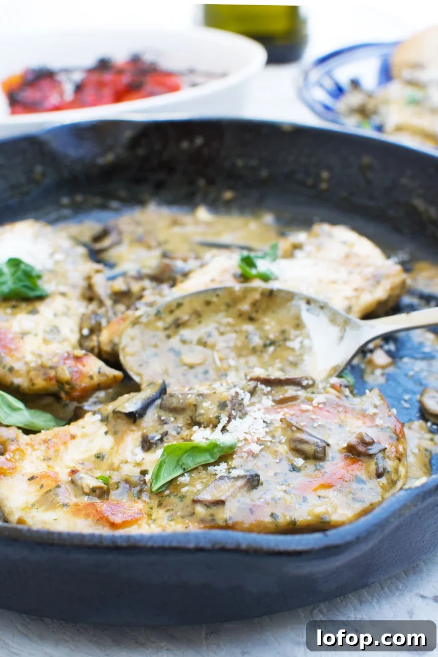 15-Minute Shanghai-Style Chicken Stir-Fry Recipe 9 a close up of some creamy pesto chicken in a cast iron skillet with a serving spoon