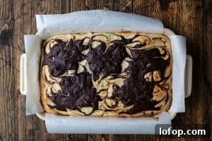 A square pan featuring a dessert with glossy chocolate swirls artistically arranged on top.