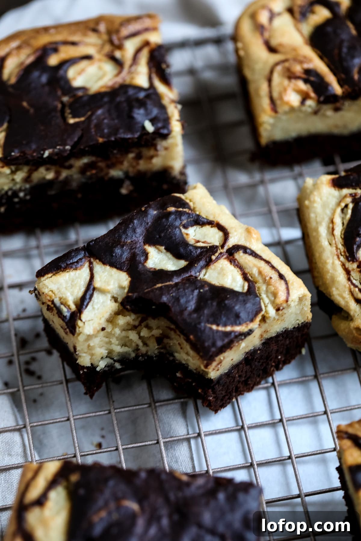 Chocolate swirl cheesecake bars cooling on a rack, showcasing rich layers of chocolate and creamy cheesecake.