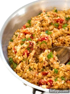 Mexican Cauliflower Rice in a metal skillet with a wooden spoon