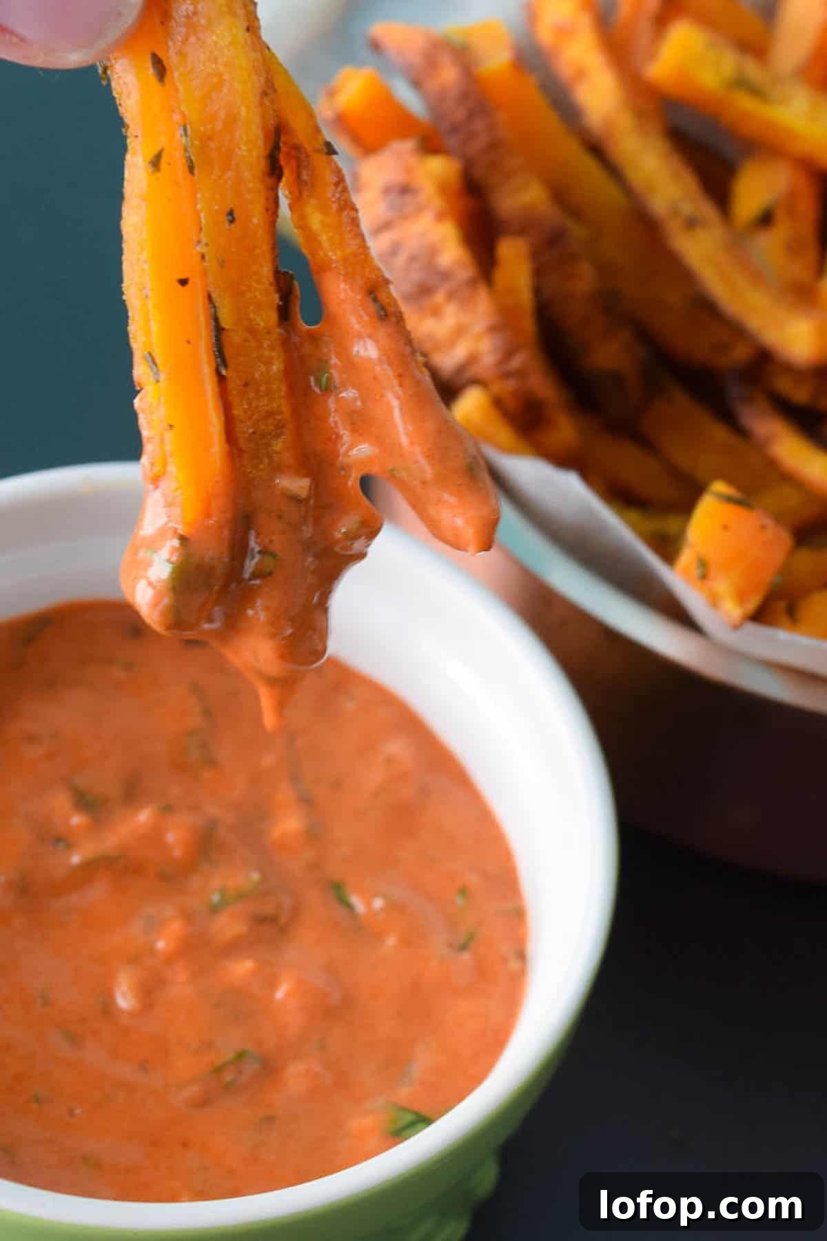 Crispy Butternut Squash Fries with Savory Magic Sauce 6 close up view of butternut squash fries being dipped into a red serving sauce