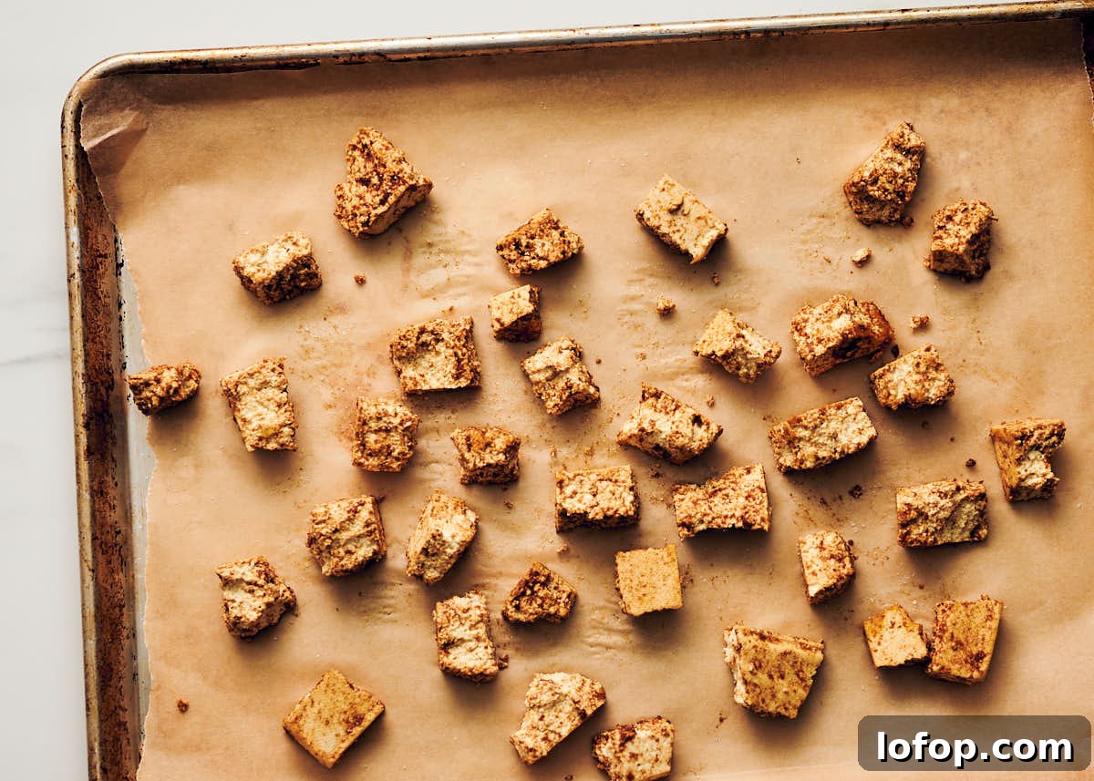 Seasoned tofu on a baking sheet about to go into the oven for veggie butter chicken.