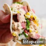 Grilled Steak Tacos with Chipotle-Lime Sauce 7 Someone holding a grilled steak taco with cilantro lime rice, grilled corn, steak and chipotle lime sauce.