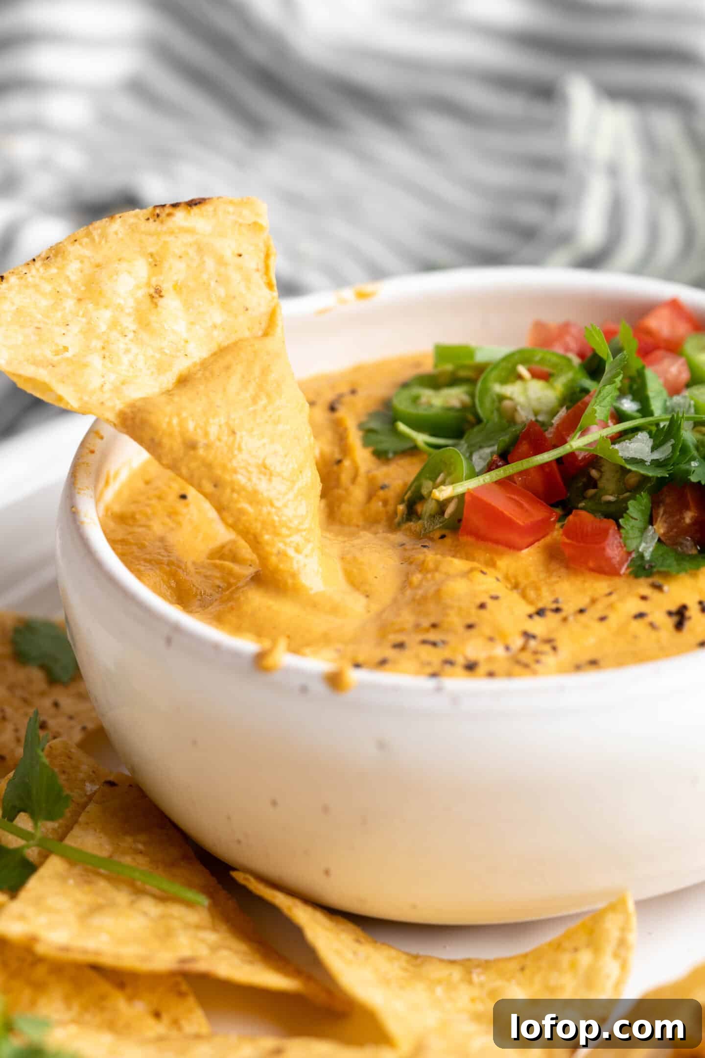 Dipping a tortilla chip into vegan queso