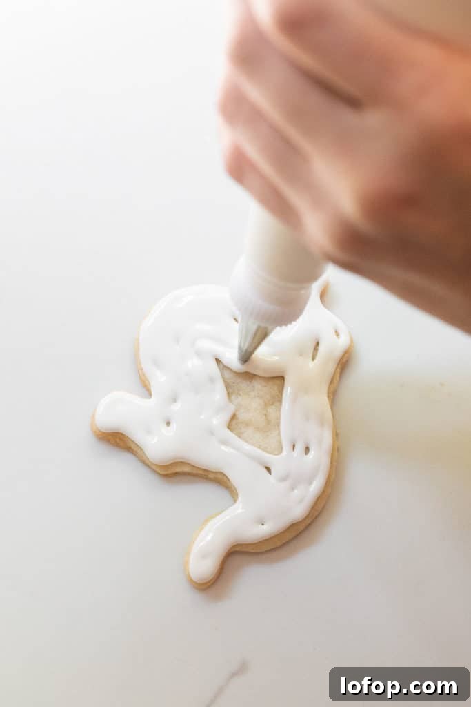 Spooky Halloween Sugar Cookie Recipe for Festive Treats 10 Adding royal icing onto a Halloween sugar cookie.