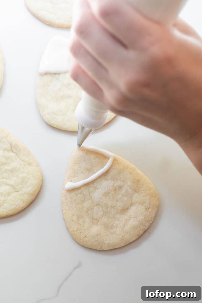 Spooky Halloween Sugar Cookie Recipe for Festive Treats 7 Piping white royal icing onto a candy corn cookie for Halloween.