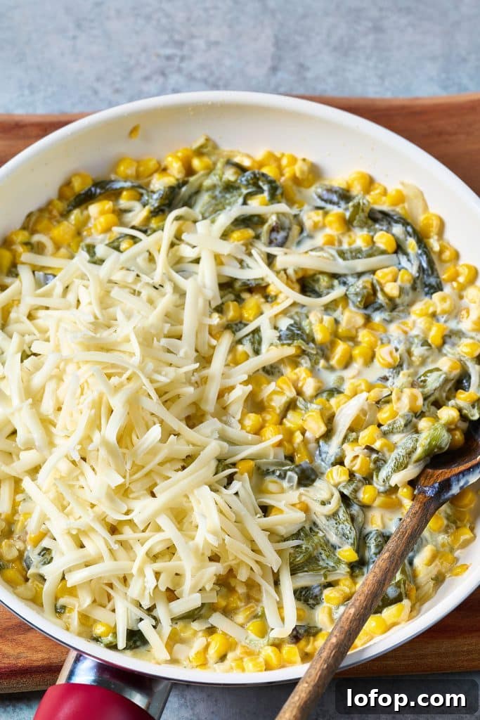 Creamy rajas topped with shredded cheese in a skillet