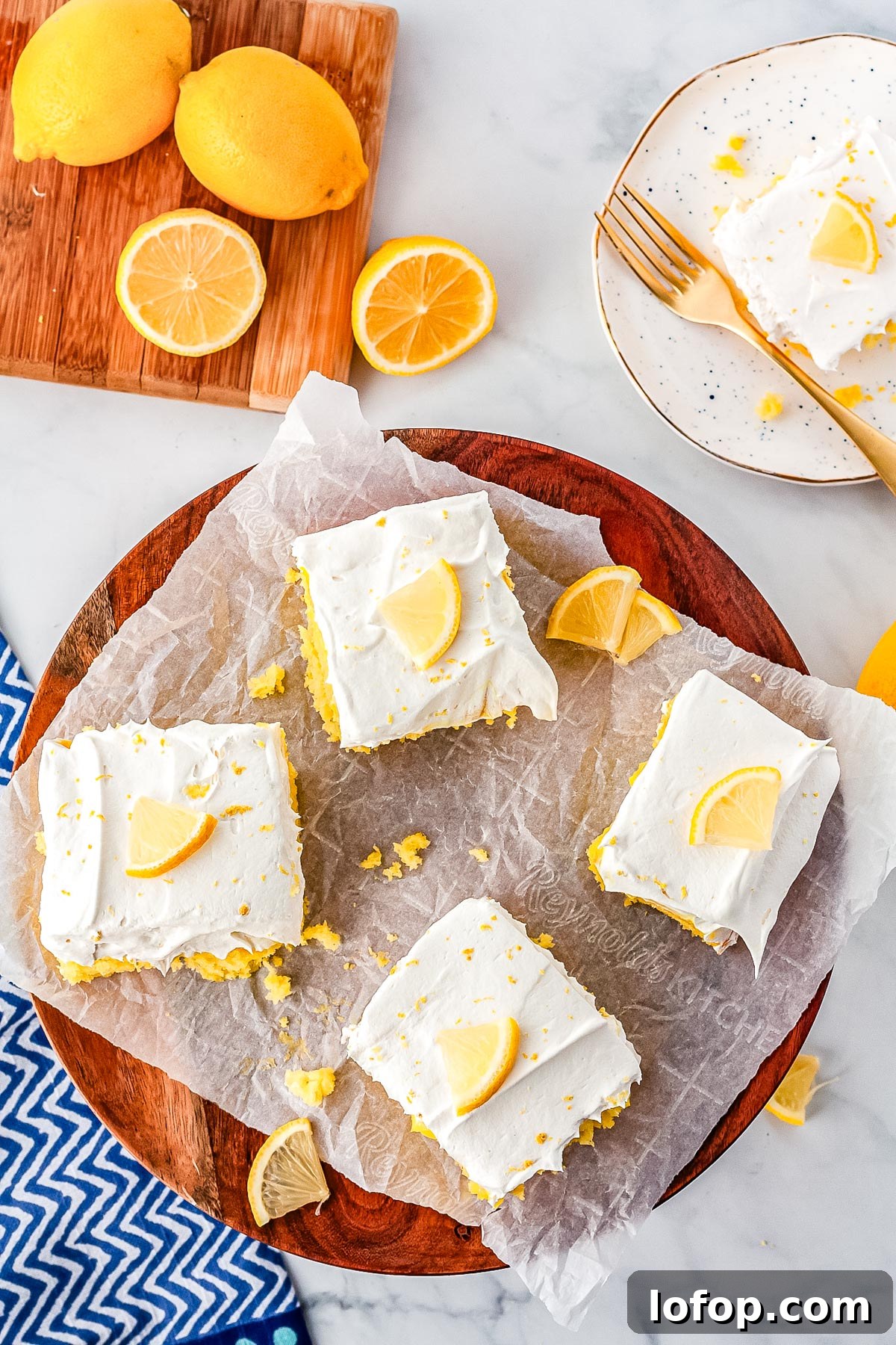 Four slices of Lemon Poke Cake on a wooden serving plate.