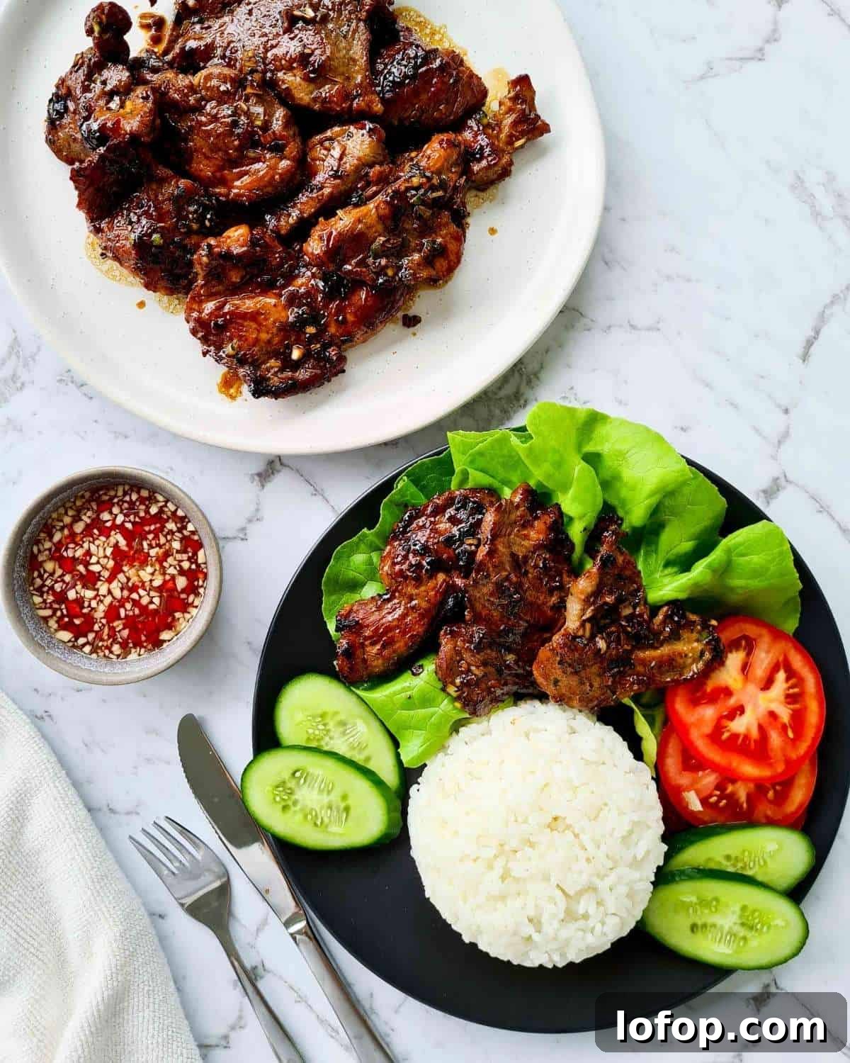 A plate of cooked pork chops and a plate of pork chops with rice and vegetables. A side of dipping sauce.