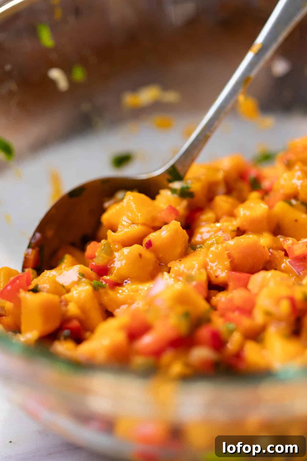 Fresh Mango Salsa Recipe: Tangy, Sweet, and Perfect for Chips 4 fresh and juicy mango salsa being mixed with with a spoon