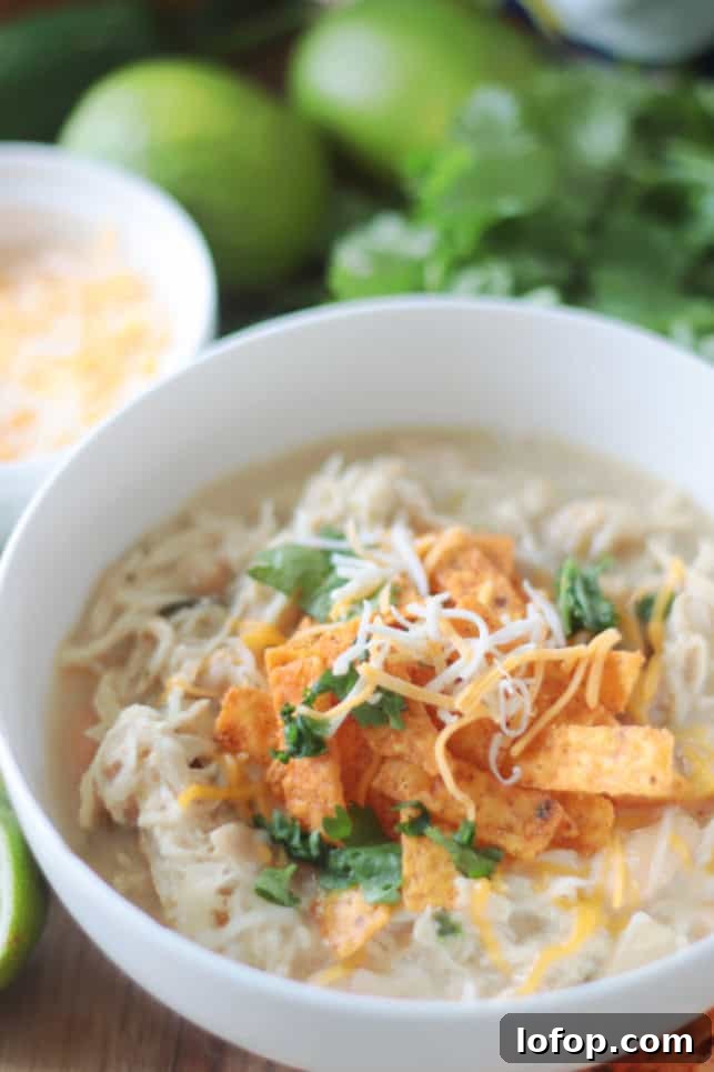 Creamy Slow Cooker White Chicken Chili (Video Recipe) 3 bowl of chicken chili with shredded cheese and tortilla strips