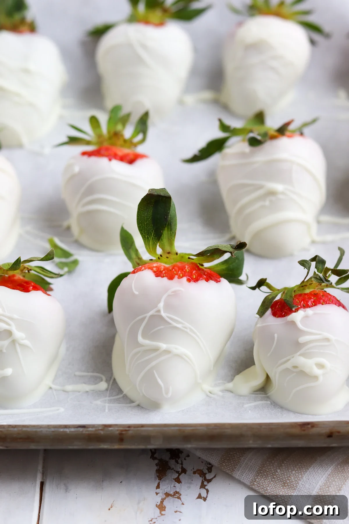 wax paper lined baking sheet with hand-dipped white chocolate strawberries.