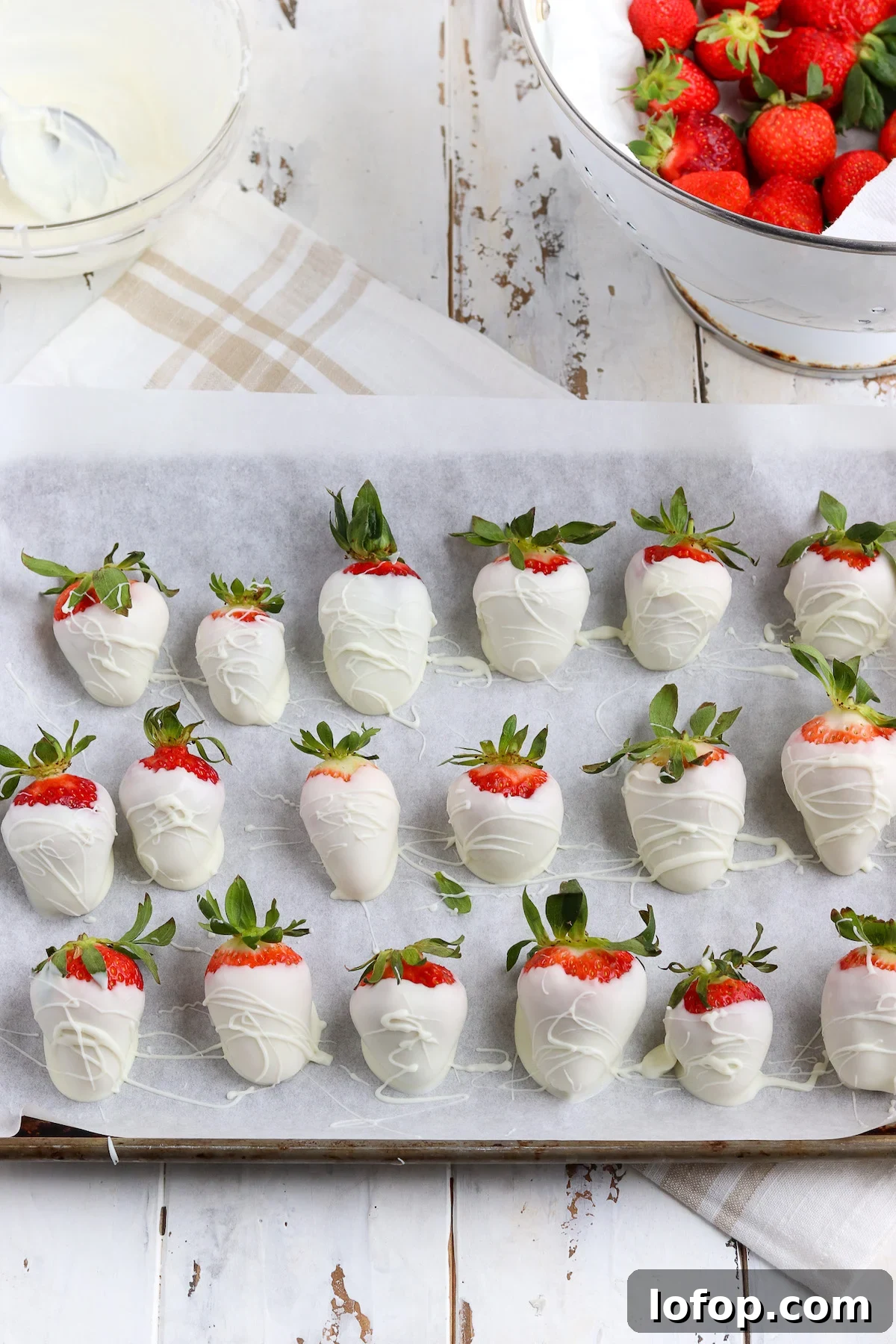 A baking sheet of homemade white chocolate covered strawberries with a professional drizzle.