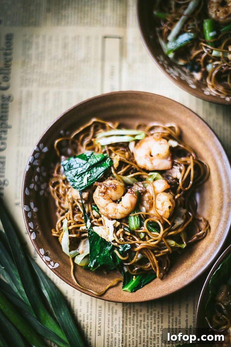 Mie Goreng Ayam on news print and surrounded by Indonesian greens