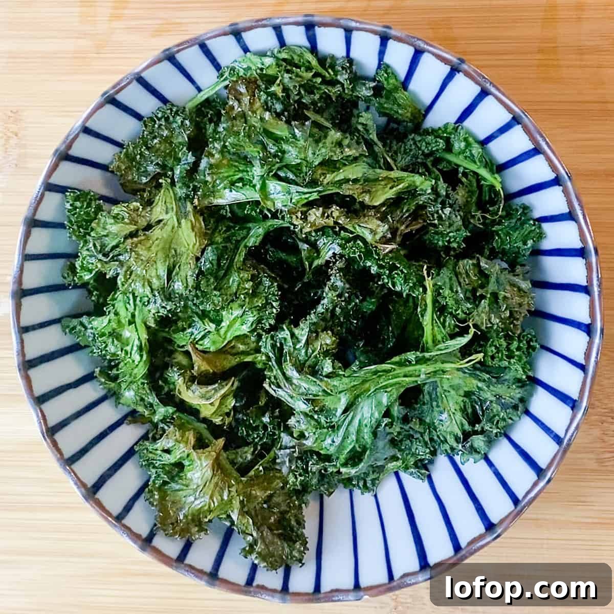 Photo of a blue and white stripy bowl filled with crispy kale.