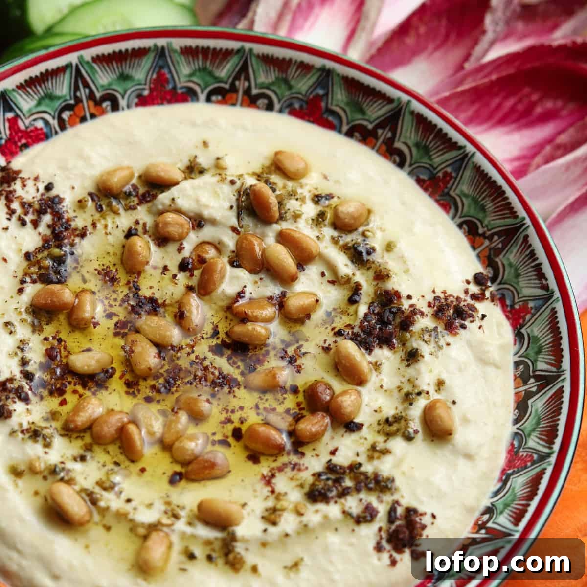 Photo of a patterned dish of hummus with toppings.