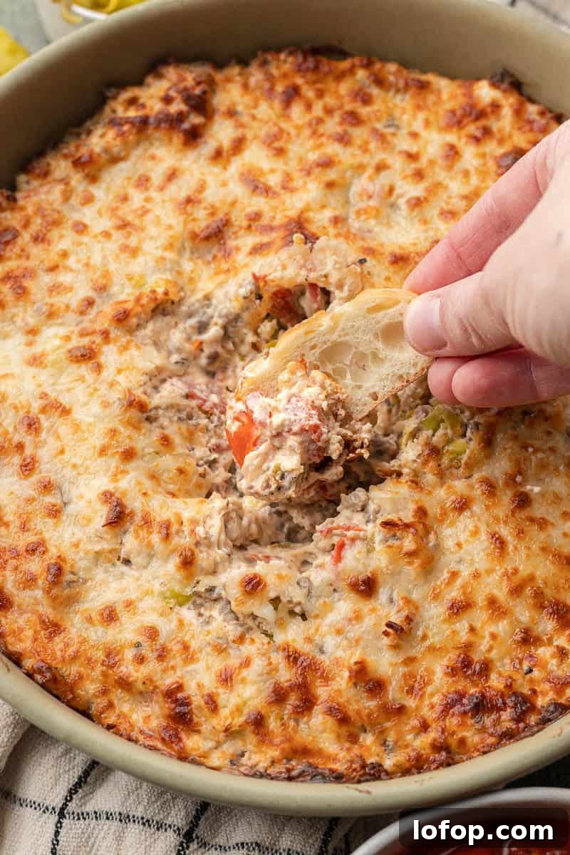 Spicy Italian Sausage Dip with hand being dipped