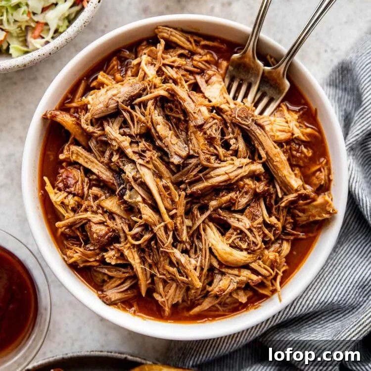 pulled pork in a white bowl with two forks.