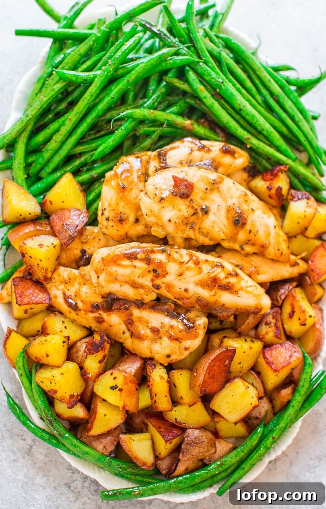 A plate with glazed chicken tenders, roasted potato cubes, and sautéed green beans arranged in separate sections.