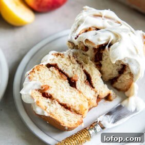apple cinnamon roll cut in half on a plate with a knife.