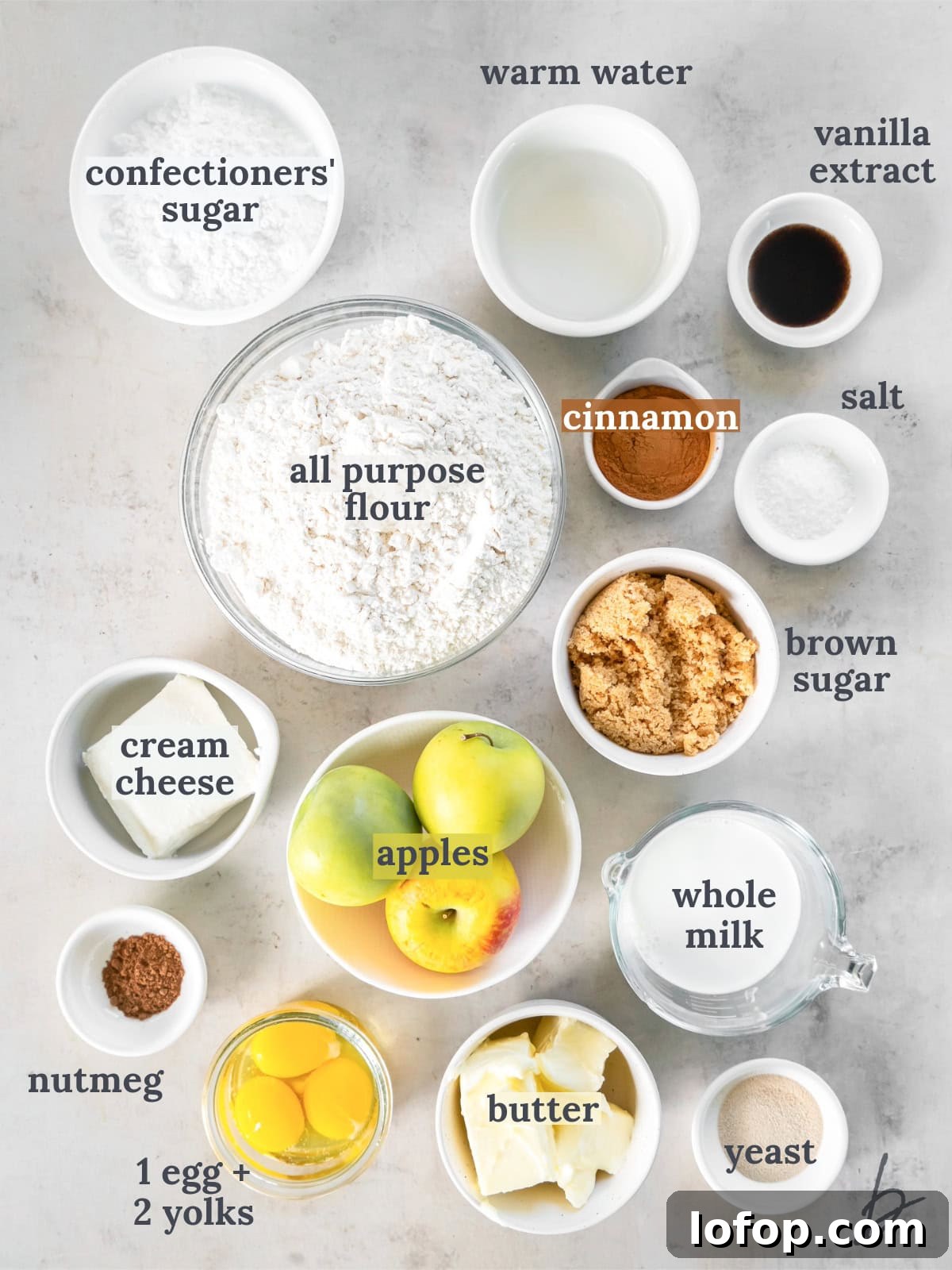 tabletop with bowls of ingredients to make apple cinnamon rolls with cream cheese icing.
