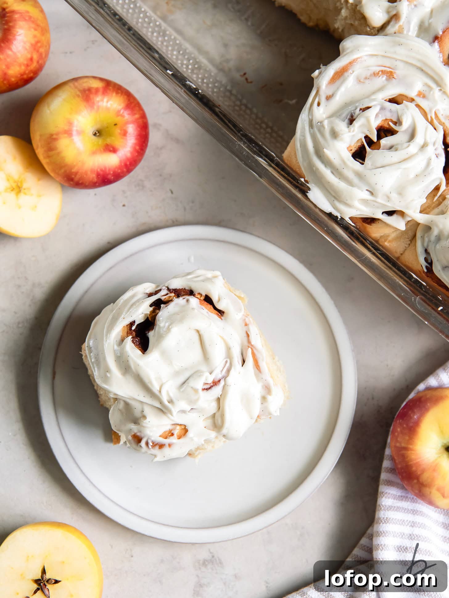 plate with apple cinnamon roll with cream cheese icing.