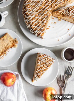 tabletop with apple coffee cake with streusel topping and a piece put on a plate.