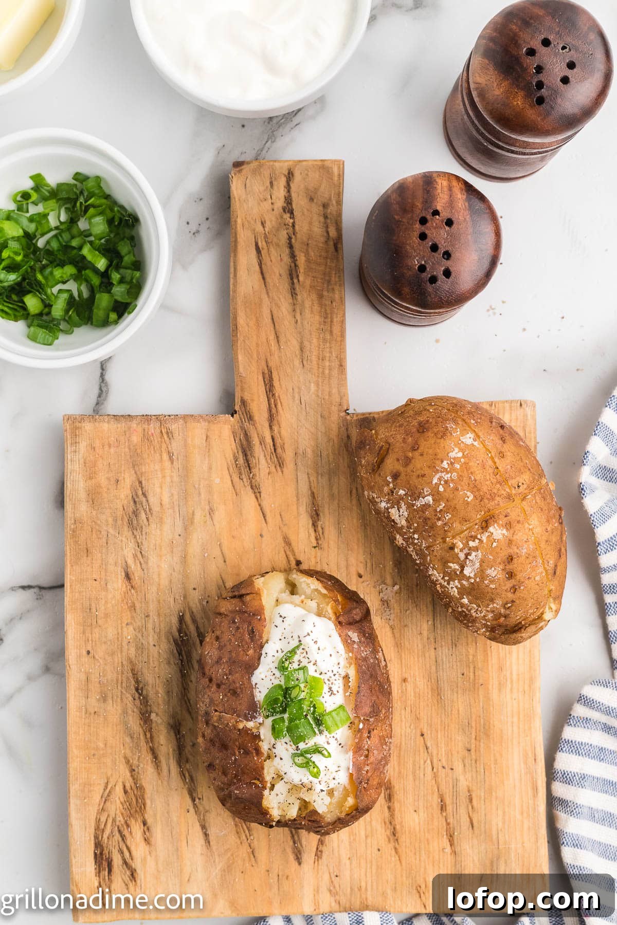 Smoked Baked Potatoes Recipe: Crispy Skins and Tender Centers 7 Smoked baked potatoes on a wooden board topped with sour cream and chives