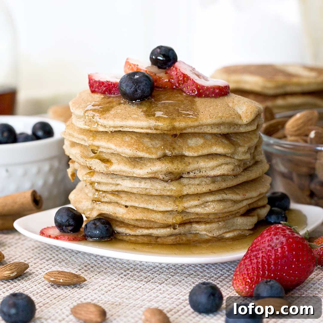 Fluffy Almond Flour Pancakes — Gluten-Free Recipe 2 A stack of fluffy almond flour pancakes with maple syrup on top.