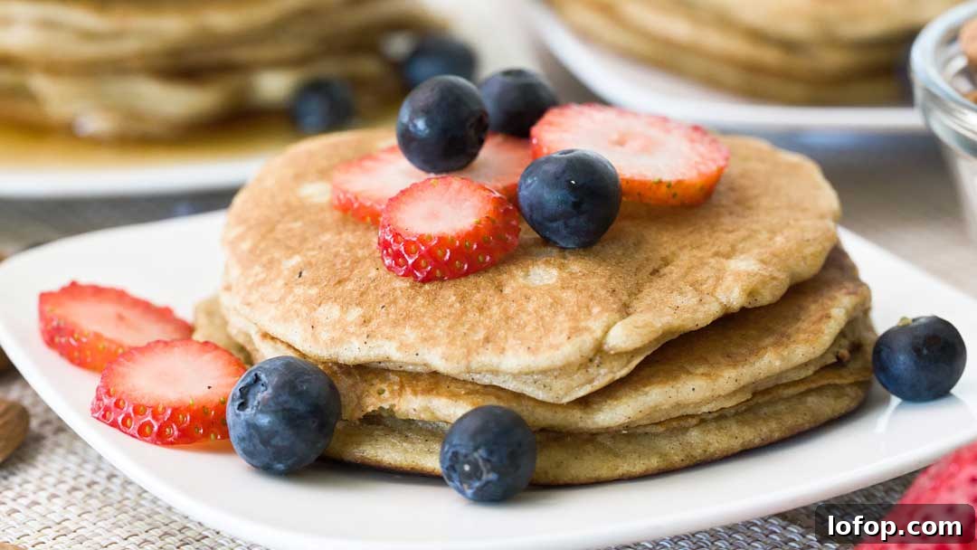 Fluffy Almond Flour Pancakes — Gluten-Free Recipe 4 A stack of three almond flour pancakes with sliced strawberries and blueberries on top.