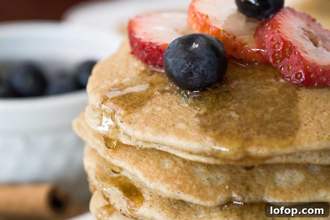 Fluffy Almond Flour Pancakes — Gluten-Free Recipe 3 A close-up of a blueberry and strawberries on top of a stack of fluffy grain-free almond flour pancakes.