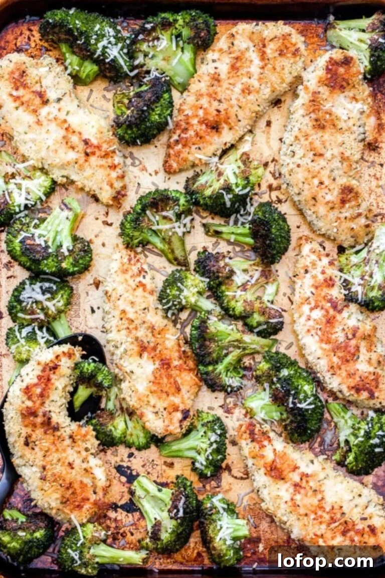 Baked parmesan-crusted chicken tenders alongside charred broccoli florets on a sheet pan.