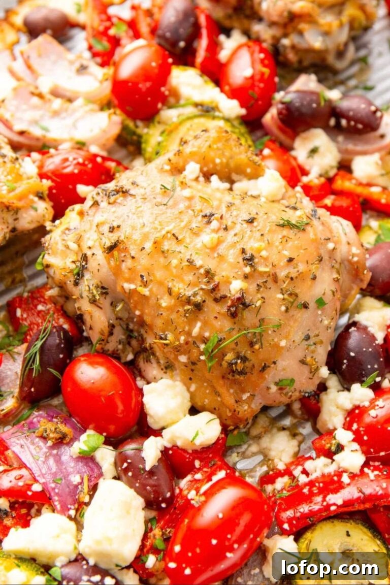 A colorful Mediterranean-inspired chicken sheet pan dinner with cherry tomatoes, zucchini, and feta cheese.