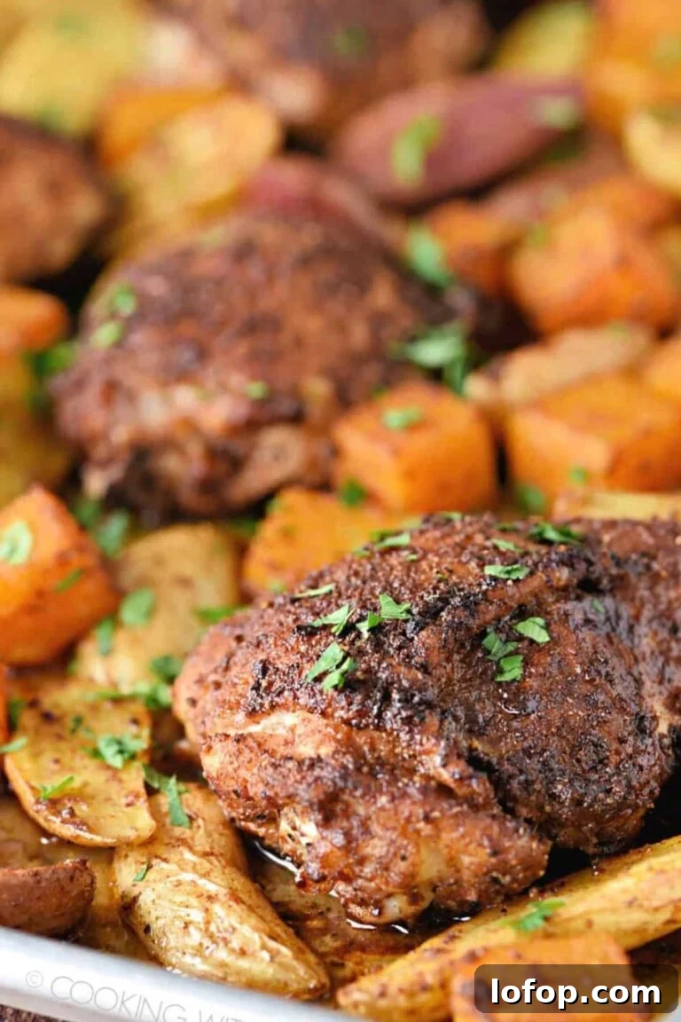 Cajun-seasoned chicken thighs with roasted potatoes and carrots, sprinkled with parsley.