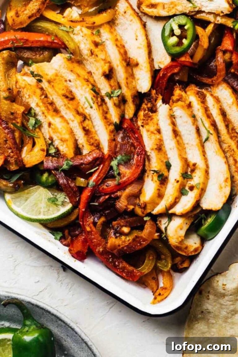 Sliced chicken fajitas with bell peppers and onions on a sheet pan, ready to serve.