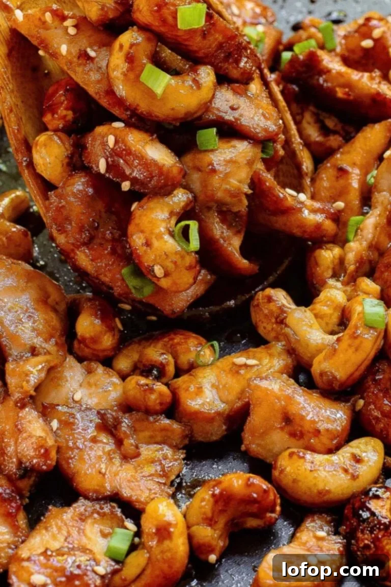 Close-up of sticky honey garlic chicken tenders with a sprinkle of sesame seeds and green onions, served on a slate plate.