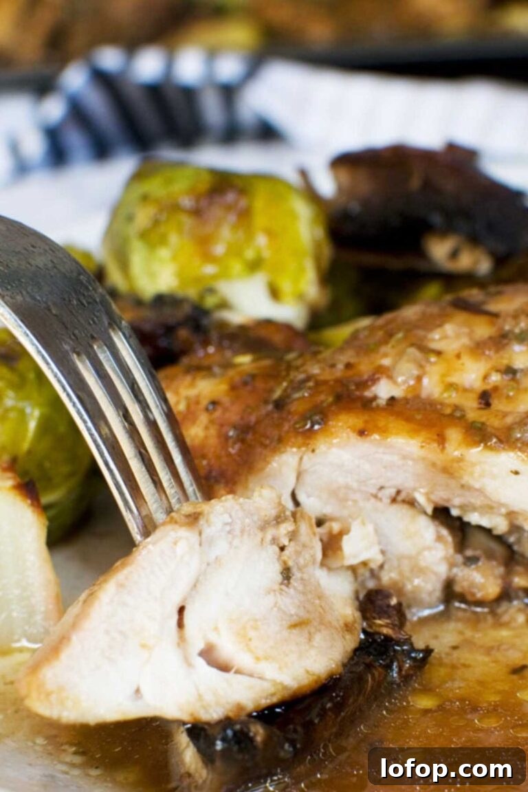 A close-up of a baked chicken breast with Brussels sprouts, showing a fork slicing through the chicken.