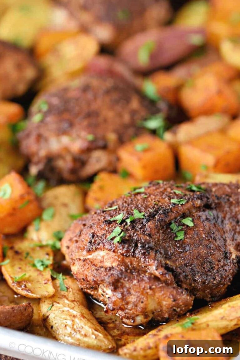 Cajun-seasoned chicken thighs with roasted potatoes and carrots, sprinkled with parsley.