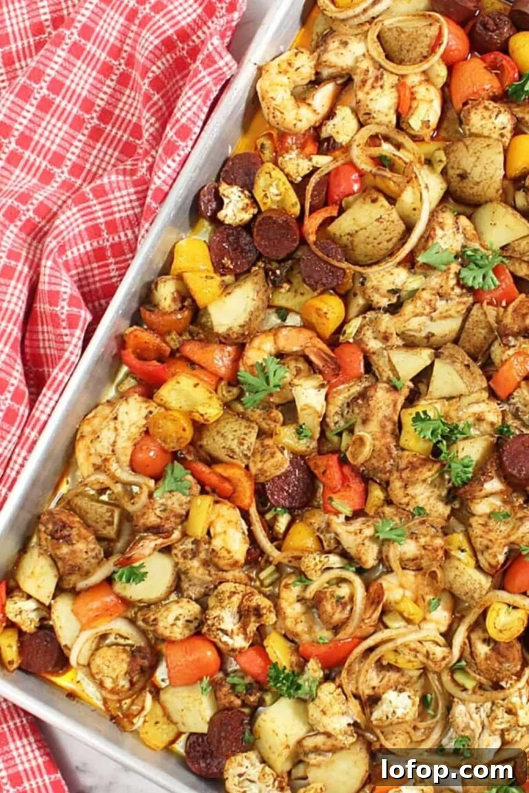 A sheet pan with lemon herb chicken, roasted tomatoes, bell peppers, and chunks of squash.