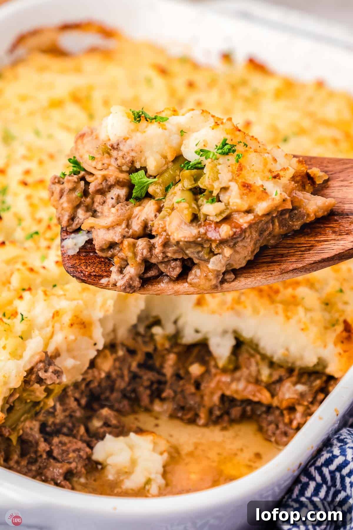 Hearty Salisbury Steak Casserole with Savory Brown Gravy 2 wood spoon with a scoop of casserole on it with a casserole dish behind it