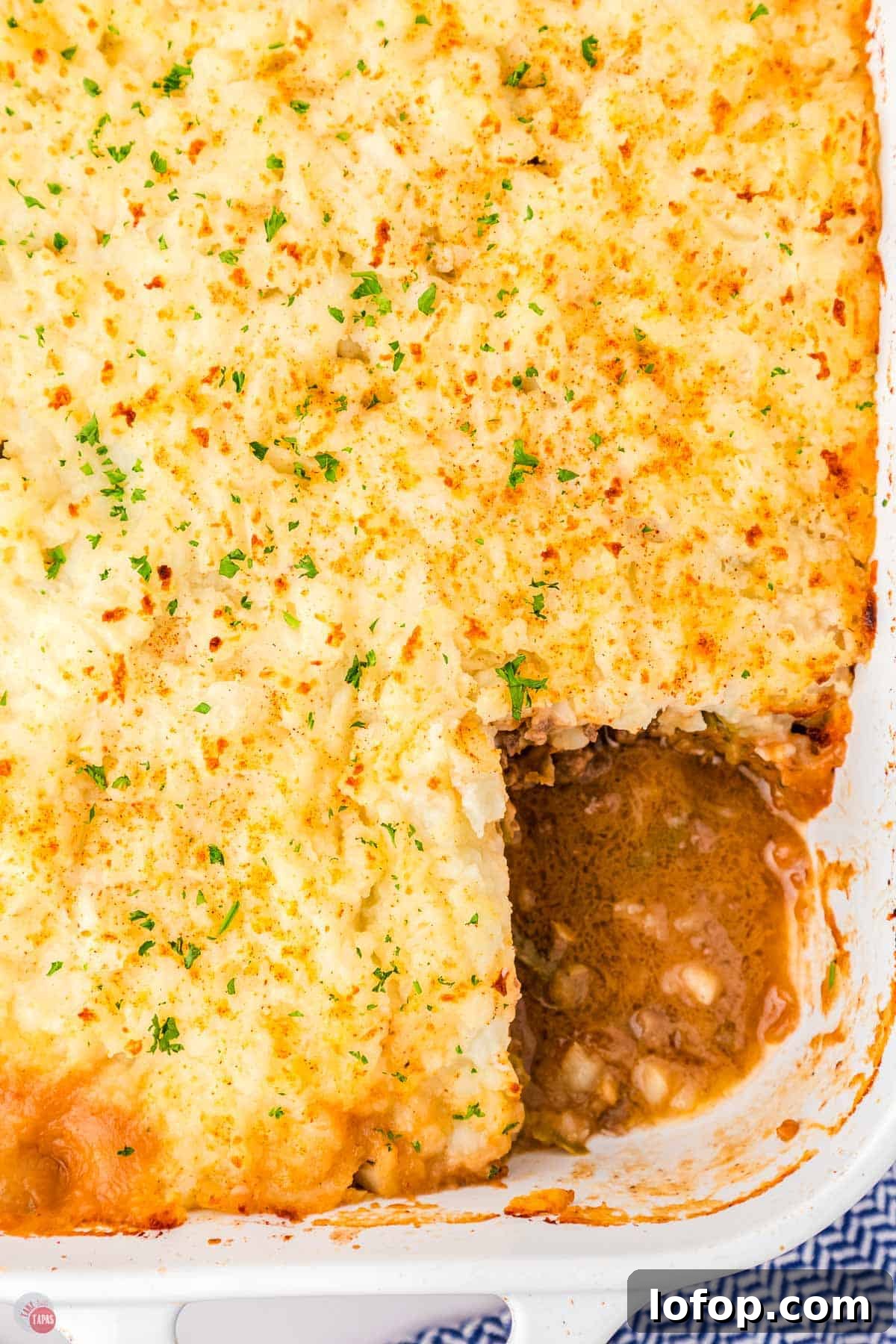 Hearty Salisbury Steak Casserole with Savory Brown Gravy 11 casserole topped with chopped parsley in a white dish with a square portion missing