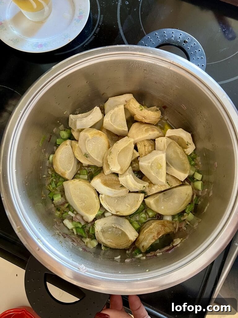 Adding the artichoke bottoms to the pot.