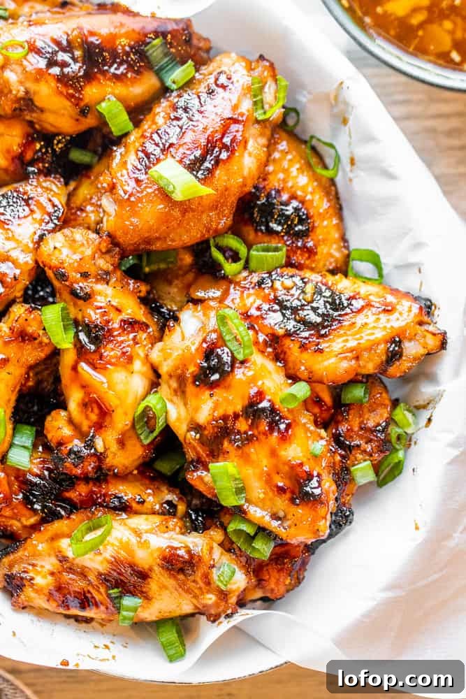 Overhead shot of chicken wings in a white bowl with peach sauce on the side.