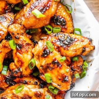 Peach wings in a white bowl on a white counter.