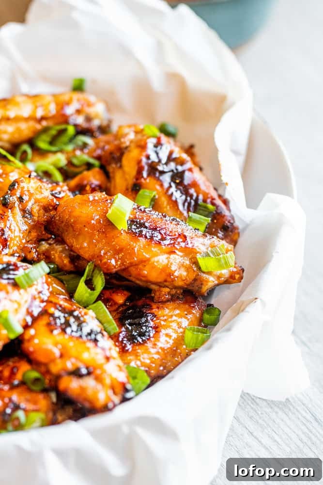 Grilled chicken wings in a white bowl on a white table.