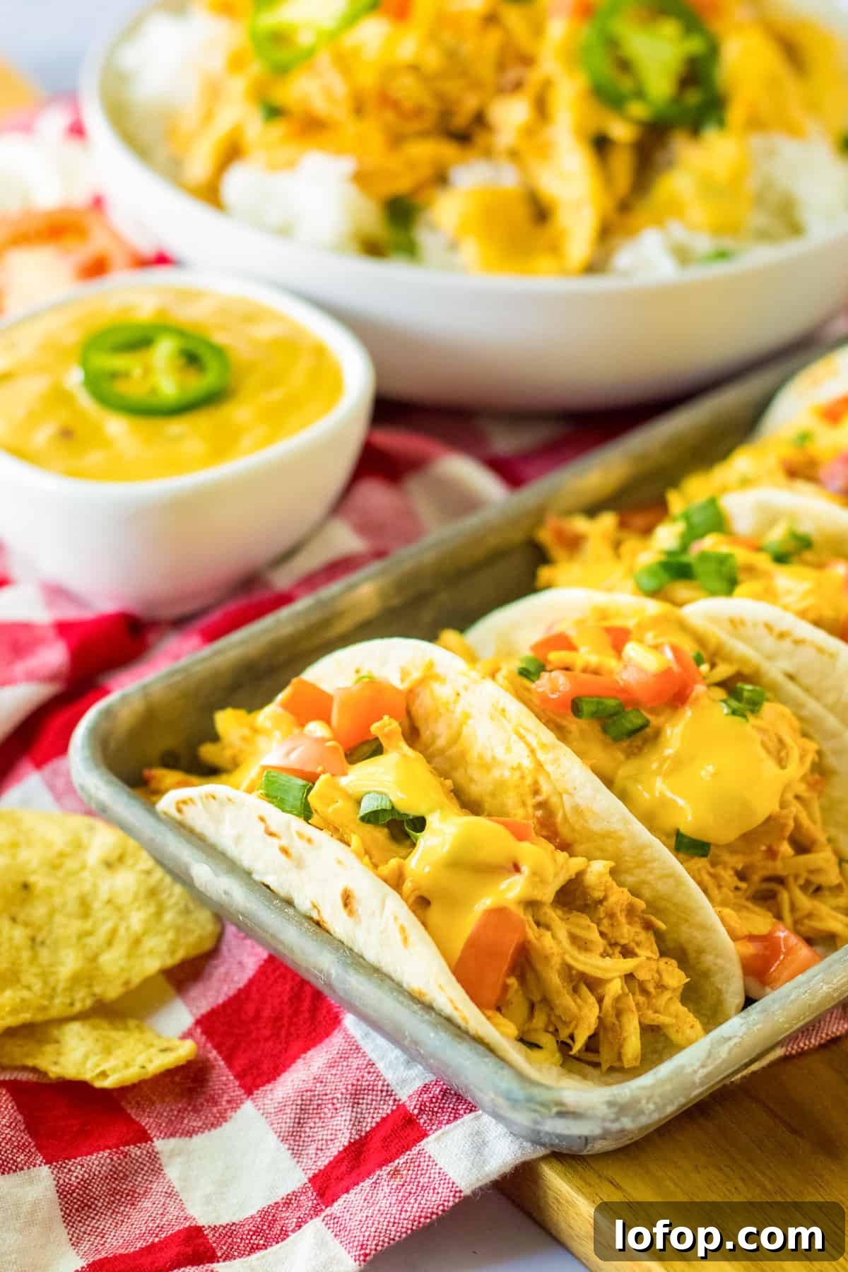 Slow cooker queso chicken tacos in flour tortillas on a serving tray.