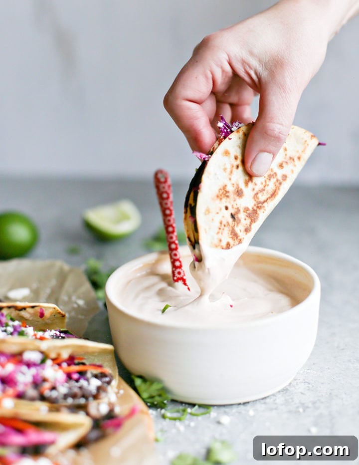 Crispy Black Bean Tacos with Cilantro-Lime Slaw 7 photo of woman dipping black bean tacos into crema