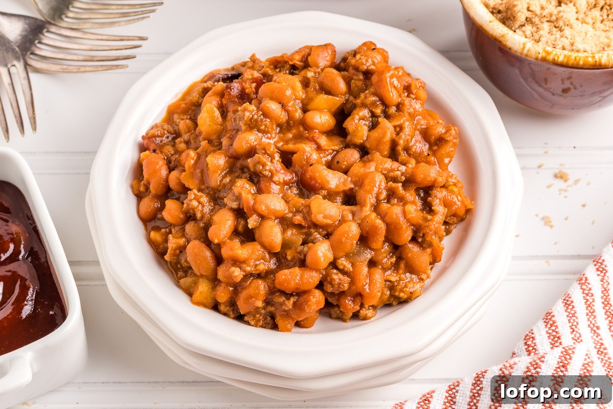 Hearty Baked Beans with Ground Beef — Stovetop, Oven or Slow Cooker 8 Side view of baked beans in white bowl.