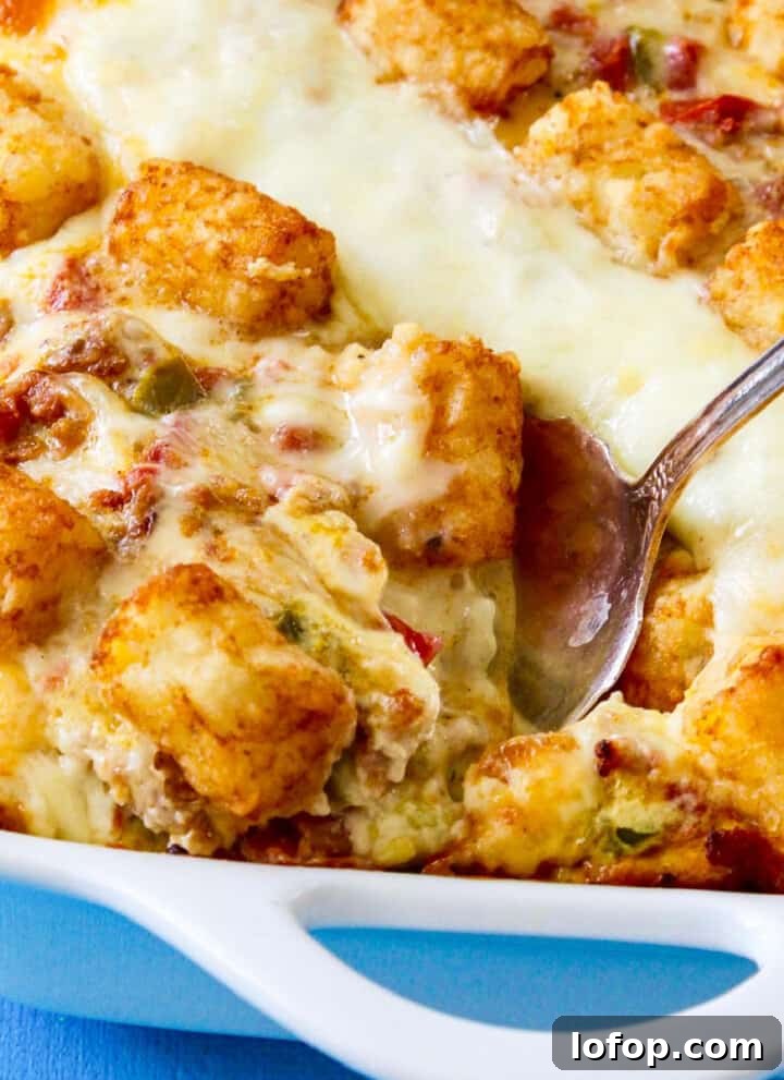 A vintage silver serving spoon taking out a piece of tater tot casserole just baked.